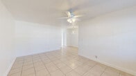Located at 1860 SW 68th Ave in Miramar, FL, this 1-bedroom, 1-bathroom residence offers a compact and efficiently designed single-floor layout. Light-colored ceramic tile flooring runs consistently throughout the entire unit, creating a cohesive and easy-to-maintain interior. The combined living and dining area serves as the central gathering space, featuring a ceiling fan with light fixture, a wall-mounted A/C unit, and a window that brings in natural light. A modern ring-style pendant chandelier distinguishes the dining area and adds a contemporary touch to the otherwise clean, minimalist aesthetic. The kitchen is bright and functional, equipped with white cabinetry, a smooth-top electric range, over-the-range microwave, refrigerator, and a window with blinds overlooking the outdoors. A hallway connects the living areas to the private spaces and is accented by a second ring pendant light fixture. The spacious bedroom includes a ceiling fan, a wall A/C unit, a window with natural light, and a closet with double panel doors. The bathroom features full-height beige tile surround on the tub/shower combo and a small window for ventilation. Throughout the unit, bright white walls and natural light contribute to an open and airy atmosphere.