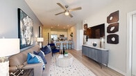 This single-story unit offers a thoughtfully planned layout that maximizes its compact footprint. The open-concept living and kitchen area serves as the heart of the space, where light wood-style luxury vinyl plank flooring, recessed lighting, and a ceiling fan create a bright, contemporary atmosphere. A glass-paneled entry door allows natural light to flow into the living area, which features a neutral color palette accented by a bold blue accent wall.

The kitchen is well-appointed with white shaker-style cabinetry, granite countertops, stainless steel appliances including a French door refrigerator, electric range, and built-in microwave. A peninsula with seating for three provides both additional prep space and a casual dining option.

A hallway connects the living area to the private bedroom, closet, and bathroom. The bedroom accommodates a full-sized bed comfortably and features dual windows with outdoor views, a ceiling fan, and plush carpet flooring. The bathroom includes a shower with a curtained enclosure and a vanity with storage. A dedicated closet and hallway complete the private quarters of this efficiently designed unit.