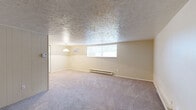 Located at 115 Timber Ridge Court in New Stanton, PA, this single-floor unit offers a practical and comfortable layout with two bedrooms and two full bathrooms. The living room is generously proportioned, featuring soft carpeting, a textured ceiling, a wall-mounted AC unit, and a pendant light fixture. Natural light filters in through windows offering outdoor views, and baseboard heating runs along the exterior walls. The kitchen is efficiently designed with white cabinetry, granite-style countertops, wood-look flooring, and black appliances including a refrigerator, electric range, and dishwasher, with a stainless sink completing the workspace. A hallway connects the kitchen to the bedroom wing, where two louvered bi-fold closet doors provide ample storage. The primary bedroom is well-sized, carpeted, and includes its own window and baseboard heat. Both bathrooms feature neutral tones; one includes a white vanity with an oval decorative mirror, while the other offers a full tub-shower combination. With four closets total throughout the unit, storage is a notable strength of this efficiently organized home.