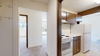 Located in Seattle's 98146 zip code, this single-floor, 2-bedroom, 1-bathroom residence offers a well-organized layout designed for comfortable everyday living. The interior features warm neutral tones throughout, with plush carpeting in the living and bedroom areas and tile flooring in the kitchen and bathroom.

The galley-style kitchen is efficiently arranged, featuring dark wood cabinetry on both upper and lower levels, white appliances including a refrigerator and electric range, a single-basin sink with white countertops, and tile flooring. A doorway from the kitchen provides convenient access to additional storage.

The spacious primary bedroom offers generous square footage, a built-in closet, and soft carpeting, creating a comfortable and functional retreat. The second bedroom is equally well-appointed with its own closet space. Both rooms are connected via carpeted hallways that provide a smooth flow throughout the unit.

The full bathroom is clean and bright, featuring a combined tub and shower unit with white surrounds, tile flooring, and chrome fixtures. Textured ceilings are consistent throughout the home.

A standout feature is the sliding glass door that opens to a private covered patio, overlooking a landscaped yard with mature shrubbery and greenery—bringing natural light and a peaceful outdoor connection to the living space.