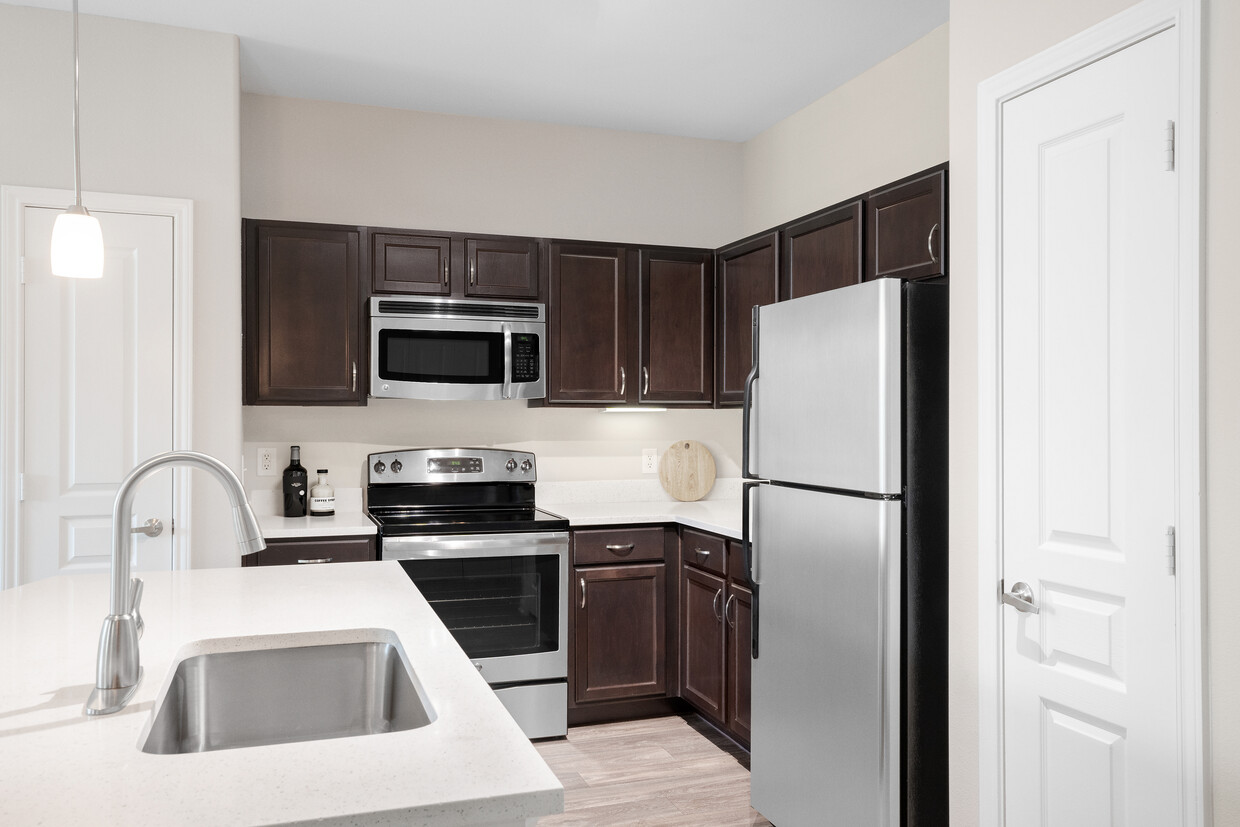 Kitchen with stainless steel appliances, quartz or granite countertops, espresso cabinetry, and hard surface vinyl plank flooring - Avalon at Pier 121