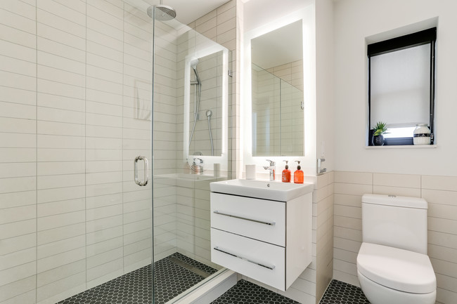 Bright tiled bathrooms with large backlit designer mirror, Hans Grohe chrome fixtures and Villeroy & Boch vanity - The Century