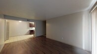 This single-floor residence offers a well-organized layout across several distinct living areas. The living room is a generously sized space finished with rich, dark hardwood-style flooring and a textured ceiling. A large sliding glass door with vertical blinds fills the room with natural light and provides direct access to the exterior. The adjacent galley-style kitchen is efficiently designed, featuring dark espresso cabinetry, granite-look countertops, a stainless steel sink, tile flooring, and stainless appliances including a refrigerator and range with an overhead exhaust hood. A tile backsplash adds a polished finishing detail.

The bedrooms are carpeted throughout and share a consistent neutral color palette. One bedroom includes a built-in desk area with shelving, offering a functional workspace, while another features a standard closet with double doors. Each room is served by a ceiling light fixture and offers window access for natural light.

The bathrooms are appointed with dark cabinetry, granite-topped vanities, framed mirrors, overhead storage cabinets, and a tub-shower combination set over tile flooring. The overall design is cohesive, blending dark wood tones with neutral walls for a clean, functional aesthetic throughout.