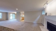 This single-floor residence offers a thoughtfully designed layout that balances comfort and functionality throughout. The spacious living area is finished with plush neutral carpeting and features crown molding, a baseboard heating system, and large windows that fill the room with natural light and offer views of lush outdoor greenery. A fireplace serves as a warm focal point within the open living space, adding character and charm.

The kitchen is well-equipped, featuring light maple cabinetry, granite-look countertops, light hardwood-style flooring, and a full suite of white appliances including a refrigerator with water dispenser, range, built-in microwave, and dishwasher. A pass-through counter connects the kitchen to the living area, enhancing the open feel of the space.

The bedrooms are generously sized, each finished with soft carpeting and crown molding, providing a calm and comfortable retreat. The primary bedroom includes access to a closet and an en-suite bathroom. Both bathrooms are finished with granite countertops, light maple vanity cabinetry, tile flooring, and large mirrors, delivering a clean and polished aesthetic.

A dedicated laundry area houses a full-sized washer and dryer with overhead shelving for added storage convenience. Throughout the residence, consistent finishes and neutral tones create a cohesive and inviting atmosphere.