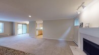 This single-floor residence offers a thoughtfully designed layout that balances comfort and functionality throughout. The spacious living area is finished with plush neutral carpeting and features crown molding, a baseboard heating system, and large windows that fill the room with natural light and offer views of lush outdoor greenery. A fireplace serves as a warm focal point within the open living space, adding character and charm.

The kitchen is well-equipped, featuring light maple cabinetry, granite-look countertops, light hardwood-style flooring, and a full suite of white appliances including a refrigerator with water dispenser, range, built-in microwave, and dishwasher. A pass-through counter connects the kitchen to the living area, enhancing the open feel of the space.

The bedrooms are generously sized, each finished with soft carpeting and crown molding, providing a calm and comfortable retreat. The primary bedroom includes access to a closet and an en-suite bathroom. Both bathrooms are finished with granite countertops, light maple vanity cabinetry, tile flooring, and large mirrors, delivering a clean and polished aesthetic.

A dedicated laundry area houses a full-sized washer and dryer with overhead shelving for added storage convenience. Throughout the residence, consistent finishes and neutral tones create a cohesive and inviting atmosphere.