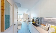 Located in the vibrant Wynwood arts district of Miami, FL, this thoughtfully designed one-bedroom, two-bathroom residence offers a clean, modern aesthetic throughout. Light wood-tone flooring runs continuously through the open-plan layout, complementing the crisp white walls and abundant natural light that pour in through floor-to-ceiling windows.

The galley-style kitchen is outfitted with flat-front white cabinetry extending to the ceiling, a sleek stone countertop, a matte black dual-basin sink, stainless steel appliances, and a distinctive grey subway tile backsplash — a polished, functional space ideal for everyday cooking.

The spacious primary bedroom is a standout, comfortably accommodating a full bedroom suite alongside a seating and dining area, all bathed in natural light from large windows with open exterior views. Its generous proportions make it a true multi-functional retreat.

Two bathrooms serve the residence, one featuring warm wood vanity cabinetry with modern fixtures and crisp tile flooring, and a second powder-style bath finished in clean white tones. Additional conveniences include two closets, a dedicated laundry area, and a utility room. The overall ambiance is bright, airy, and contemporary — well-suited to Miami's dynamic urban lifestyle.