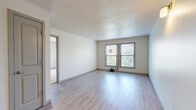 Located at 1735 W 19th St in Lawrence, Kansas, this one-bedroom, one-bathroom unit offers a well-organized single-floor layout designed for comfortable everyday living. The open-concept living and kitchen area is anchored by light wood-style laminate flooring that extends throughout the main living spaces, creating a clean and cohesive aesthetic. A textured ceiling and neutral white walls provide a bright, airy backdrop, while dual windows allow natural light to filter in and offer views of the surrounding greenery.

The kitchen is thoughtfully positioned in a recessed nook and features stainless steel appliances, including a refrigerator, electric range, and over-the-range microwave, complemented by white cabinetry and a light-toned countertop. A pass-through counter connects the kitchen to the living area, enhancing the open feel. A ceiling fan adds practicality to the living space.

A hallway with wood-style flooring leads to the generously sized bedroom, which transitions to plush carpet underfoot. The bedroom is well-lit by two corner windows with outdoor views and includes a closet alongside a stylish sliding barn door that opens to the full bathroom. The bathroom features standard fixtures in a compact, functional arrangement. Overall, the unit presents a clean, move-in-ready space with practical finishes throughout.
