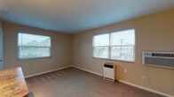 Located at 1428 King Ave in Columbus, Ohio's Grandview Heights area, this single-floor unit offers a practical and functional layout throughout. The spacious main living area is finished with wall-to-wall carpeting and neutral beige walls, creating a warm and inviting atmosphere. Multiple windows fitted with horizontal blinds allow generous amounts of natural light to fill the room, offering views of the surrounding neighborhood. A wall-mounted air conditioning unit and a freestanding heater provide year-round climate control.

The secondary room, also carpeted and similarly finished, includes a closet and a window overlooking the exterior, making it well-suited for use as a bedroom or home office. A compact kitchen is visible in the layout, featuring a breakfast bar pass-through that connects it to the main living space, along with cabinetry and hardwood-style flooring.

The bathroom is clean and efficiently designed, with a white vanity and a full bathtub and shower combination enclosed in a white surround. The overall interior maintains a consistent, understated aesthetic with neutral tones and white trim throughout, offering a move-in-ready canvas adaptable to a variety of furnishing styles.