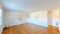 Located at 5314 Whetstone Rd in North Chesterfield, Virginia, this single-story, 2-bedroom, 1-bathroom home offers a straightforward and functional layout with consistent warm-toned hardwood flooring throughout. The living room is a bright, open space featuring clean white walls, natural light from large windows, and a connection to the rest of the home via a central hallway. Adjacent to the living area, the combined kitchen and dining space is well-appointed with white cabinetry, a stainless steel refrigerator, a gas range, a dishwasher, and a window above the sink that brings in natural light and outdoor views of surrounding greenery. The primary bedroom is a generously sized room featuring a wide sliding-door closet, hardwood floors, and a doorway connecting to the hallway. The second bedroom mirrors the same clean aesthetic, offering its own closet, a window with natural light, and hardwood flooring. The bathroom includes a full tub-shower combination with white tile surround, chrome fixtures, a grab bar, and a window that provides ventilation and natural light. With four closets distributed throughout the home, storage is a practical highlight. The home's neutral palette and consistent hardwood floors create a cohesive, move-in-ready atmosphere.