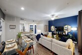 Located at 1895 Barker Cypress Rd in Houston, TX, this well-appointed 2-bedroom, 2-bathroom residence offers a thoughtfully designed single-floor layout. The open-concept living and dining area serves as the heart of the home, highlighted by rich wood-style flooring, a bold navy accent wall, and a ceiling fan that anchors the space. The kitchen features white shaker cabinetry, granite countertops, stainless steel appliances, a double-basin sink, and tile flooring, creating a clean and functional workspace. The primary bedroom is generously sized, continuing the navy accent wall theme, with carpet flooring, a ceiling fan, and a large window that invites natural light. It is complemented by a walk-in closet with wire shelving. The second bedroom offers a warm, neutral palette with carpet flooring and its own ceiling fan. Both bathrooms are finished with granite-topped white vanities, tile flooring, and tasteful decor — one featuring a shower/tub combo. A dedicated in-unit laundry room with a washer and dryer adds everyday convenience. The cohesive navy, gold, and gray design palette carries throughout the home, lending a modern and polished ambiance.