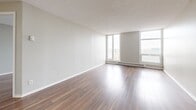 Located on the 11th floor at 450 Rue Sherbrooke E in Montréal's vibrant Le Plateau-Mont-Royal area, this well-appointed one-bedroom, one-bathroom unit offers a thoughtfully designed single-level layout. Rich hardwood-style flooring flows throughout the main living areas, complemented by neutral grey walls and textured ceilings that create a clean, contemporary ambiance.

The open-concept kitchen and living area forms the heart of the unit. The kitchen is equipped with stainless steel appliances, including a full-size refrigerator and electric range, white cabinetry, a dark granite-style countertop, a central island for additional prep space, and tile flooring. This flows seamlessly into a bright and airy living area featuring large floor-to-ceiling windows that flood the space with natural light and offer open city views, with baseboard heating along the perimeter.

The generously sized primary bedroom is a comfortable retreat, also featuring hardwood-style flooring, soft neutral tones, and a large window that continues the theme of natural light throughout the unit. The bathroom is finished with white tile, a full soaking tub with shower, and clean, classic fixtures. This unit offers a practical and bright urban living experience in one of Montréal's most sought-after neighbourhoods.