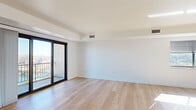 Located at 5 Grand View Ave in Pittsburgh's Mount Washington neighborhood, this single-floor residence offers a clean, modern interior with a bright and airy atmosphere throughout. The main living area is finished with light-toned hardwood flooring and crisp white walls, creating an open and welcoming feel. Large black-framed sliding glass doors lead to a private balcony, allowing natural light to fill the space while providing views of the surrounding cityscape.

The galley-style kitchen features warm wood cabinetry, dark granite countertops, stainless steel appliances including a refrigerator and dishwasher, and recessed lighting overhead. It connects seamlessly to the main living area via a hardwood-floored corridor.

The bedrooms are carpeted for comfort and each includes a built-in closet with louvered bifold doors and sturdy shelving and hanging rods for ample storage. The floor plan, visible in the dollhouse view, reveals an efficient L-shaped layout with well-defined living, sleeping, and utility zones.

Two bathrooms serve the residence. One features marble-look tile floors and walls, a glass-enclosed walk-in shower, a dark wood vanity with granite countertop, and modern chrome fixtures. The second includes a tiled tub-shower combination with safety grab bars and a matching granite-top vanity, offering practical functionality.