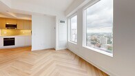 Located in the heart of Toronto's Financial District at 166 Pearl St, this thoughtfully designed unit makes excellent use of its compact footprint across a single floor. The layout is efficient and modern, with light-toned herringbone-patterned hardwood flooring flowing seamlessly throughout, lending a refined, contemporary character to the space.

The living area is bright and airy, anchored by large floor-to-ceiling windows that frame striking panoramic views of the Toronto skyline and surrounding cityscape. Crisp white walls and recessed lighting enhance the sense of openness, while a sleek sliding glass-panel closet adds practical storage without compromising the clean aesthetic.

The kitchen is integrated along one wall of the corridor, featuring flat-front white lower cabinetry, warm wood upper cabinets with a matching backsplash in a rich amber tone, built-in stainless steel appliances including an oven and microwave, and a minimalist black-fixture sink — a polished, functional design suited to urban living.

The bathroom offers a spa-like atmosphere with sage green subway-tiled walls surrounding a soaking tub with a shower, matte black fixtures, a dark wood vanity, and light terrazzo-style floor tiles — delivering a calming, well-finished retreat. The overall ambiance of the unit is clean, contemporary, and filled with natural light.