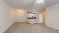 Located at 800 Gunn Rd in Centerville, Georgia, this single-floor residence offers a well-organized layout designed for comfortable everyday living. The open-concept living and dining area forms the heart of the home, finished with plush wall-to-wall carpeting, crown molding, and ceiling fans throughout. A elegant chandelier anchors the dining space, while the adjoining kitchen is accessible via a pass-through counter with a dark laminate breakfast bar. The galley-style kitchen is well-appointed with white cabinetry featuring gold hardware, dark countertops, wood-look vinyl flooring, and white appliances including a range, microwave, and refrigerator. The bedrooms are generously sized, each with soft carpeting, ceiling fans, and ample natural light provided by large windows fitted with horizontal blinds. One bedroom includes a walk-in closet, while another benefits from dual windows on adjoining walls. The bathrooms feature wood-look vinyl flooring, white vanities, and one includes a soaking tub with a tiled surround. The textured ceilings and warm neutral tones throughout lend the space a cohesive and inviting ambiance.