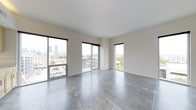 This single-floor space showcases a clean, contemporary design characterized by its open layout and minimalist aesthetic. The polished concrete floors run throughout, lending an industrial yet refined quality to the interior while reflecting the abundant natural light that pours in from multiple directions.

Large, floor-to-ceiling windows and a sliding glass door are positioned across two walls, framing impressive views of the surrounding urban skyline and cityscape. The generous window placement ensures the space is bathed in natural light throughout the day, enhancing the sense of openness and volume.

The smooth, white walls and bright white ceiling complement the industrial flooring, creating a neutral canvas well-suited to a variety of uses. The corner window configuration captures panoramic city views from multiple angles, making the urban environment a defining visual feature of the space.

The overall ambiance is modern and airy, with the elevated position above street level contributing to a sense of privacy while maintaining strong visual connectivity to the city below. The unfinished, open-plan nature of the space offers flexibility for customization.