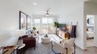 This well-designed single-floor residence showcases a clean, contemporary aesthetic throughout its open-concept layout. The kitchen is outfitted with stainless steel appliances, including a side-by-side refrigerator with ice and water dispenser, a built-in microwave, an electric range, and a wine cooler. White shaker-style cabinetry extends to the ceiling, complemented by a mosaic tile backsplash, white quartz countertops, a peninsula with an integrated sink, and light hardwood-style flooring. A pendant light and track lighting add functional illumination throughout.

The living area is bright and welcoming, featuring a ceiling fan, recessed lighting, and large sliding glass doors that open onto a private balcony with open views of the surrounding landscape. The space flows naturally into a dining area, creating an ideal setting for both entertaining and everyday living.

The bedroom is a calm retreat with plush carpet, a ceiling fan, large windows with blinds and drape panels, and ample natural light. A walk-in closet offers generous storage.

The en-suite bathroom features a wide dual-sink vanity with white cabinetry and gold-toned hardware, wood-look flooring, a full-width mirror, and access to the walk-in closet. The overall ambiance of the residence is modern, airy, and thoughtfully finished throughout.