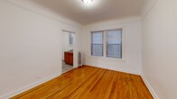 This 590 square foot apartment in Chicago offers a blend of compact living and classic charm. The space comprises two bedrooms, one bathroom, a living room, and a kitchen, all efficiently arranged on a single floor. The primary bedroom is notably spacious at 190 square feet, providing ample room for comfort.

Throughout the apartment, gleaming hardwood floors add warmth and character, contrasting beautifully with the crisp white walls. Large windows in the bedrooms and living area flood the space with natural light, enhancing the sense of openness. Architectural details such as arched doorways and classic baseboards contribute to the apartment's vintage appeal.

The updated kitchen, while compact, features wooden cabinetry and modern appliances, including a gas range. The bathroom, though not expansive, is functional and includes a pedestal sink and a combination of tile and hardwood flooring.

Radiators in the rooms hint at the building's history while providing efficient heating. The apartment's layout, with its connecting hallways, offers a sense of separation between living spaces. Overall, this property presents a cozy yet functional urban living space, balancing modern updates with timeless architectural elements.