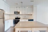 This one-bedroom, one-bathroom unit at 3445 Berkley St in Alexandria, VA offers a thoughtfully designed layout that maximizes every square foot of living space. The open-concept kitchen and combined dining and living area form the heart of the home, anchored by rich hardwood-style flooring and a clean, contemporary aesthetic throughout. The kitchen is outfitted with crisp white shaker cabinetry extending to the ceiling, light quartz countertops, a subway tile backsplash, and a full suite of stainless steel appliances including a refrigerator, electric range, built-in microwave, and dishwasher. A central track lighting fixture adds a modern touch overhead. The spacious bedroom features plush wall-to-wall carpeting and large windows that flood the room with natural light and offer views of the surrounding greenery. The bathroom is finished with large-format neutral tile in the tub-shower surround, a white vanity with quartz countertop, and brushed nickel fixtures. Additional highlights include four closets providing abundant storage, an in-unit laundry area, a welcoming entrance, and a dedicated hallway connecting the private spaces. The unit presents a bright, neutral palette throughout, creating a clean and comfortable living environment.
