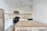 This one-bedroom, one-bathroom unit at 3445 Berkley St in Alexandria, VA offers a thoughtfully designed layout that maximizes every square foot of living space. The open-concept kitchen and combined dining and living area form the heart of the home, anchored by rich hardwood-style flooring and a clean, contemporary aesthetic throughout. The kitchen is outfitted with crisp white shaker cabinetry extending to the ceiling, light quartz countertops, a subway tile backsplash, and a full suite of stainless steel appliances including a refrigerator, electric range, built-in microwave, and dishwasher. A central track lighting fixture adds a modern touch overhead. The spacious bedroom features plush wall-to-wall carpeting and large windows that flood the room with natural light and offer views of the surrounding greenery. The bathroom is finished with large-format neutral tile in the tub-shower surround, a white vanity with quartz countertop, and brushed nickel fixtures. Additional highlights include four closets providing abundant storage, an in-unit laundry area, a welcoming entrance, and a dedicated hallway connecting the private spaces. The unit presents a bright, neutral palette throughout, creating a clean and comfortable living environment.