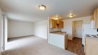 Located at 103 E Wedgewood Ave in Spokane, WA, this single-floor unit offers a practical and comfortable layout designed for everyday living. The open-concept living and dining area is finished with neutral-toned carpeting and textured ceilings, creating a bright and airy atmosphere. A peninsula counter seamlessly connects the living space to the kitchen, which features warm wood-tone cabinetry with ample upper and lower storage, laminate countertops, a stainless steel sink, and a dishwasher. Wood-look flooring in the kitchen and entry areas adds a durable, easy-to-maintain surface in high-traffic zones. The living area benefits from a large sliding glass door that opens to a private balcony, flooding the space with natural light and offering pleasant outdoor views. A wall-mounted air conditioning unit ensures year-round comfort. The bedrooms are carpeted and well-sized, each featuring windows that bring in natural light and baseboard heating for efficient warmth. The bathroom includes a tub-shower combination with tiled surrounds and built-in shelving. Throughout the unit, the clean, neutral palette and functional design provide a versatile foundation well-suited to a variety of living arrangements.