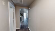 This single-floor residence offers a thoughtfully designed layout that balances functionality and modern style. An arched hallway entry with dark hardwood-style flooring leads into the main living areas, setting an inviting tone throughout the space.

The kitchen serves as a central highlight, featuring rich dark-wood cabinetry, granite countertops, stainless steel appliances including a refrigerator, range, microwave, and dishwasher, and a kitchen island with pendant lighting overhead. The open design connects seamlessly to the living area, making it ideal for both everyday use and entertaining.

The bedrooms offer a contrast in flooring, transitioning to plush carpet for added comfort. Each bedroom benefits from natural light provided by slatted blinds on the windows, and at least one bedroom includes a ceiling fan with a light fixture. A walk-in closet with built-in hanging rods is featured in one of the bedrooms, providing generous storage capacity.

The bathrooms are finished with dark-wood vanities, dark granite countertops, undermount sinks, and framed mirrors. One bathroom features a private water closet configuration, while another presents a clean, efficient layout with hardwood-style tile flooring. A laundry area with washer and dryer hookups is also present within the unit.