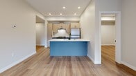 This contemporary residence in Kelowna, BC, offers 74 square meters of thoughtfully designed living space. The single-story home boasts four bedrooms and two bathrooms, making it an ideal choice for families or those requiring extra space. The interior is characterized by a modern, open-concept layout, enhancing the sense of spaciousness and flow between rooms.

The home features warm wood-look flooring throughout, creating a cohesive and inviting atmosphere. Large windows in the bedrooms provide ample natural light and offer picturesque views of the surrounding landscape. The primary bedroom, measuring 11 square meters, ensures a comfortable retreat for homeowners.

The kitchen is a standout feature, showcasing light-colored cabinetry, stainless steel appliances, and a striking blue island that serves as both a focal point and functional workspace. Subway tile backsplash and recessed lighting add to the kitchen's contemporary appeal.

Bathrooms are equipped with modern fixtures, including a sleek glass shower enclosure and floating vanities. Space-saving sliding doors are utilized in some areas, maximizing the usable floor space. The neutral color palette throughout the home provides a blank canvas for personalization while maintaining a clean, fresh aesthetic.

Overall, this property combines functionality with modern design, offering a comfortable living space in a desirable Kelowna location.