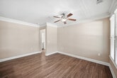 This 760-square-foot, one-bedroom, one-bathroom apartment at 4000 Penuche Way in Holly Springs, NC is thoughtfully designed to maximize comfort and functionality on a single floor. The open-concept living and kitchen area features warm hardwood-style flooring, crown molding, and ceiling fans, while multiple large windows with blinds flood the space with natural light and offer outdoor views. The galley-style kitchen is outfitted with cream cabinetry, granite countertops, stainless steel appliances including a refrigerator, oven, and dishwasher, and a single-basin sink. The living and dining areas are spacious and bright, with pendant lighting accenting the layout. The 180-square-foot bedroom is carpeted, includes a ceiling fan, and connects to two closets—one of which is a walk-in with wire shelving. The bathroom features wood-style flooring, a cream vanity with ample cabinet storage, and a full tub/shower combo. A dedicated laundry room with upper cabinetry accommodates a full-size washer and dryer. With neutral tones, quality finishes, and practical storage throughout, this apartment delivers a clean, comfortable living environment.