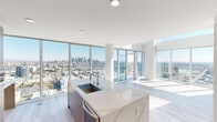 This sophisticated two-story residence offers an expansive, light-filled layout across two well-proportioned floors, combining modern design with breathtaking panoramic city views. Floor-to-ceiling glass windows wrap the living areas, flooding the interiors with natural light and framing dramatic skyline vistas that stretch to the horizon.

The open-concept kitchen and living area serve as the heart of the home, featuring a large waterfall-edge marble island with an integrated sink, warm wood cabinetry, high-gloss white upper cabinets, a professional-grade stainless steel range, and a built-in microwave tower. The seamless flow between cooking and living spaces makes this an ideal setting for both everyday living and entertaining.

The primary bedroom suite is exceptionally generous in scale, bathed in sunlight through a wide bank of floor-to-ceiling windows overlooking the cityscape. It includes a dedicated walk-in closet with custom built-in shelving and hanging rails. The three bathrooms are finished in a clean, contemporary palette, with at least one featuring a frameless glass-enclosed walk-in shower with tile surround and recessed lighting.

Throughout the residence, light wood-tone flooring, crisp white walls, and recessed lighting maintain a consistent, refined aesthetic. Every detail reflects a commitment to modern urban luxury.