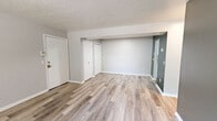 This single-floor unit offers a practical and efficiently organized layout, accommodating four bedrooms, one bathroom, and a dedicated kitchen within a compact footprint. The common area features light gray walls, clean white trim, and durable wood-look plank flooring that extends throughout, giving the space a fresh, modern feel. Multiple doors from the main living area provide easy access to the bedrooms and closet spaces, contributing to a well-connected floor plan. The galley-style kitchen is thoughtfully appointed with white cabinetry, light granite-look countertops, a double stainless steel sink, and white appliances, including a refrigerator and range. The layout makes efficient use of every inch of counter and cabinet space. The bedrooms are carpeted and neutral in tone, each featuring textured ceilings and natural light from windows with blinds. Several bedrooms include built-in closets with hanging rods and shelving, offering functional storage. One bedroom features a walk-in closet with dual shelving rails and carpeted flooring. The bathroom is straightforward, featuring a full tub-shower combo with chrome fixtures. Throughout the unit, the clean, neutral palette and consistent finishes create a cohesive, move-in-ready environment suited for shared or multi-occupant living.
