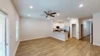 This two-story residence offers three bedrooms and two and a half bathrooms across a thoughtfully arranged floor plan. The main level features an open-concept living and kitchen area with warm wood-look vinyl plank flooring, recessed lighting, and ceiling fans that enhance airflow and comfort throughout. The kitchen is well-appointed with crisp white shaker cabinetry, granite-look countertops, a center island with a sink, and a full suite of stainless steel appliances including a range, over-the-range microwave, and French door refrigerator. A pantry provides additional storage. A convenient half bathroom is located on the main floor, ideal for guests. The entry hallway flows naturally from the front door toward the living area, with the staircase positioned along one side. Upstairs, the bedrooms each feature wood-look flooring and closets with double-panel doors and built-in rods for organization. The full bathrooms include a tub-shower combination with built-in shelving. The home also includes an attached garage with an automatic opener, offering secure and convenient parking or additional storage space. The clean, neutral color palette throughout creates a bright and cohesive living environment.