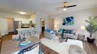This single-floor residence is designed with a modern, open-concept layout that seamlessly connects the main living areas. The living room is a comfortable, well-lit space featuring crown molding, wood-look flooring, a ceiling fan, and multiple windows that allow natural light to fill the room. A distinctive arched niche adds architectural character to one wall, while direct access to a dining area completes the social space.

The kitchen is outfitted with stainless steel appliances, including a refrigerator, electric range, and microwave. Two-tone cabinetry—white uppers paired with dark lower cabinets—frames the space, complemented by a subway tile backsplash and light quartz countertops. A peninsula with bar seating connects the kitchen to the dining area, making it functional for both cooking and entertaining.

The bedrooms are carpeted and generously sized, each featuring large windows that bring in natural light. The primary bedroom provides access to an en-suite bathroom equipped with a soaking tub, dark vanity cabinetry, white countertops, and wood-look flooring. A second full bathroom offers similar finishes with a tub-shower combination. A dedicated laundry room houses a full-size top-load washer and dryer, adding practical everyday convenience.