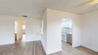 Located on NW 35th Street in Pompano Beach, Florida, this single-story unit presents a clean, modern aesthetic with thoughtful updates throughout. Light-toned wood-look vinyl flooring runs continuously across the living areas and bedrooms, creating a cohesive and low-maintenance foundation throughout the space.

The living area connects to the kitchen through a pass-through window with a built-in ledge, offering an open, communicative layout. The kitchen itself is well-equipped, featuring high-gloss white upper cabinetry that extends to the ceiling for maximum storage, contrasted by warm wood-tone lower cabinets. Light quartz-style countertops, a stainless steel sink, and white appliances including an electric range, built-in microwave, and dishwasher complete the functional workspace.

The bedrooms are generously sized with neutral walls, textured ceilings, and ample closet space accessed through louvered bifold doors fitted with wire shelving systems. A ceiling fan is present in one bedroom area.

Two bathrooms serve the unit. One features a tub and shower combination enclosed by sliding frosted glass doors with decorative tile accents, paired with a wood-tone vanity and bright mirror. The second bathroom offers a matching vanity with light countertop, large mirror, and wood-look flooring, maintaining design consistency throughout.