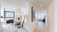 Located at 700 Northeast 1st Avenue in the heart of downtown Miami, this modern one-bedroom, two-bathroom residence offers a thoughtfully designed open-concept layout with clean lines and contemporary finishes. Light wood-tone flooring flows throughout, complemented by crisp white walls that enhance the bright, airy atmosphere.

The living room is a standout, featuring expansive floor-to-ceiling glass windows that wrap around the corner, flooding the space with natural light and framing dynamic views of Miami's urban skyline. The kitchen is sleek and functional, outfitted with stainless steel appliances, white cabinetry, a large center island with bar seating, and bold pendant lighting — ideal for both cooking and entertaining.

The bedroom offers a serene retreat with large sliding glass doors, generous natural light, and access to outdoor views. A dedicated workspace nook provides added versatility. The two bathrooms are finished in a clean, minimalist style — one featuring a glass-enclosed walk-in shower with white tile surround and wood-look flooring, and the other with a backlit vanity mirror and modern fixtures.

A dedicated closet and additional storage complete the practical layout. The overall ambiance is polished and contemporary, reflecting the vibrant energy of its downtown Miami location.