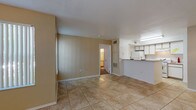 This single-floor residence offers a practical and comfortable layout designed for everyday living. The open living and dining area is finished with neutral-toned tile flooring and warm beige walls, creating a bright and welcoming atmosphere. A raised breakfast bar connects the living space to the galley-style kitchen, which features light wood cabinetry, ample counter space, a stainless steel sink, and white appliances including a refrigerator and range. Under-cabinet lighting adds functionality to the workspace.

The two bedrooms are carpeted for comfort and each includes a ceiling fan with light fixture and windows dressed with vertical blinds that allow for natural light. One bedroom also features a sliding mirrored closet, enhancing the sense of space.

The primary bathroom includes a tiled shower-tub combination and direct access to a walk-in closet with built-in shelving and wood-look flooring. The secondary bathroom is similarly appointed with a shower-tub combo, a single vanity with a large mirror, and tile flooring. Both bathrooms maintain a clean, utilitarian design. Overall, the layout flows efficiently, offering a functional and move-in ready living environment.