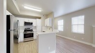 This single-floor residence is designed with a clean, contemporary aesthetic characterized by neutral warm-beige tones, light wood-style flooring, and an abundance of natural light throughout. The open-concept layout connects the kitchen and living area seamlessly, creating a welcoming, airy atmosphere.

The kitchen is well-equipped with stainless steel appliances, including a gas range, microwave, and refrigerator, complemented by crisp white cabinetry, a classic subway tile backsplash, and a peninsula with a built-in sink that provides additional counter space and casual dining potential.

The spacious living area features light wood-style flooring, multiple windows that invite generous natural light, and a fireplace with a built-in display niche above, serving as a functional focal point. An additional room with large windows and light flooring offers flexibility as a dining or office space.

The bedrooms are carpeted for comfort and include ample natural light from well-positioned windows. A generous walk-in closet with wire shelving systems provides organized storage. The bathrooms are finished with white vanities, light countertops, and chrome fixtures; one features a tub-shower combo, while the other offers a separate vanity area adjacent to a tub-shower.
