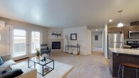 This thoughtfully designed single-floor residence offers a comfortable and functional layout across several well-defined living spaces. The expansive living room serves as the heart of the home, featuring plush carpeting, a sleek fireplace, and large windows that invite natural light. French doors open to the outside, enhancing the room's airy feel, while a wall-mounted mini-split unit ensures year-round climate comfort.

The kitchen is a standout space, showcasing rich dark wood cabinetry, a granite-topped island with pendant lighting, stainless steel appliances including a dishwasher, and warm hardwood-style flooring that flows seamlessly into the adjacent dining area. The dining space is accented by a pendant light fixture and a large mirror, creating an inviting atmosphere for meals and gatherings.

Two well-sized bedrooms offer carpeted floors and ample natural light. Each bathroom is finished with wood-toned vanity cabinetry and hardwood-style flooring; one features a glass-enclosed walk-in shower, while the other includes a full tub and shower combination. Neutral tones and clean lines throughout the residence create a cohesive, modern aesthetic that is both practical and welcoming.