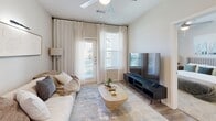 This one-bedroom, one-bathroom unit in Conroe, Texas offers a thoughtfully designed layout that maximizes its compact footprint. The open-concept kitchen and living area forms the heart of the unit, with light wood-look flooring flowing throughout. The kitchen features a contemporary two-tone design, pairing crisp white upper cabinets with warm wood-grain lower cabinetry, complemented by a white tile backsplash, light quartz countertops, and a full suite of stainless steel appliances, including a dishwasher, electric range, microwave, and refrigerator.

The living area is bright and inviting, benefiting from multiple windows and a glass door that fill the space with natural light. Ceiling fans are present throughout the unit. Neutral-toned walls contribute to an airy, cohesive aesthetic.

The bedroom features plush carpeting, a ceiling fan, and a well-sized window with outdoor views. It connects directly to the full bathroom, which includes wood-look flooring, dark wood cabinetry, a tiled shower-tub combination, and direct access to a dedicated walk-in closet with built-in shelving. A separate laundry area completes the unit's functional offerings, making this a well-rounded and efficiently organized living space.