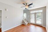 This two-story home in Saint Charles, Missouri offers a well-organized layout spread across two floors. The main level features a living room with warm hardwood flooring, a ceiling fan, and large French doors that allow abundant natural light and provide outdoor views. A staircase with a white balustrade connects the two floors, adding a clean, classic architectural touch. The kitchen is efficiently designed with white cabinetry, dark countertops, a tile backsplash, and stainless steel appliances including a range, microwave, and dishwasher. A closet and a bathroom are also located on the main floor, with the bathroom featuring white cabinetry, a single-basin vanity, and a large mirror with stylish lighting fixtures. Upstairs, two bedrooms provide comfortable retreats — the primary bedroom features hardwood flooring, a ceiling fan, and an open layout, while the second bedroom is finished with plush carpet and a window that brings in natural light. A second full bathroom on the upper level mirrors the clean, neutral aesthetic found throughout the home, complete with white cabinetry and a well-lit vanity. Neutral gray walls, consistent hardwood flooring on the main level, and thoughtful details throughout give this home a cohesive, move-in-ready appeal.