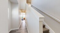 Located on SE 3rd St in Blue Springs, Missouri, this contemporary multi-story home offers three bedrooms, two bathrooms, and well-appointed living spaces spread across three floors. The main living area features light gray wood-look flooring, a ceiling fan, and abundant natural light from sliding glass doors that open to an outdoor deck. The open layout seamlessly connects the living room and dining area to the kitchen, which is outfitted with crisp white shaker cabinets, granite countertops, a granite tile backsplash, and stainless steel appliances including a refrigerator, dishwasher, and range. Carpeted staircases with clean white railings and recessed lighting connect the floors, with well-lit hallways guiding the way to each level. The generously sized primary bedroom features plush carpet, multiple windows that flood the room with natural light, and access to a spacious walk-in closet fitted with wire shelving. The bathrooms are finished with granite-topped white vanities, large mirrors, and wood-look flooring. Additional closet space provides ample storage throughout. The home's neutral color palette, modern fixtures, and consistent use of quality materials create a clean, bright, and welcoming atmosphere throughout.