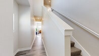 Located on SE 3rd St in Blue Springs, Missouri, this contemporary multi-story home offers three bedrooms, two bathrooms, and well-appointed living spaces spread across three floors. The main living area features light gray wood-look flooring, a ceiling fan, and abundant natural light from sliding glass doors that open to an outdoor deck. The open layout seamlessly connects the living room and dining area to the kitchen, which is outfitted with crisp white shaker cabinets, granite countertops, a granite tile backsplash, and stainless steel appliances including a refrigerator, dishwasher, and range. Carpeted staircases with clean white railings and recessed lighting connect the floors, with well-lit hallways guiding the way to each level. The generously sized primary bedroom features plush carpet, multiple windows that flood the room with natural light, and access to a spacious walk-in closet fitted with wire shelving. The bathrooms are finished with granite-topped white vanities, large mirrors, and wood-look flooring. Additional closet space provides ample storage throughout. The home's neutral color palette, modern fixtures, and consistent use of quality materials create a clean, bright, and welcoming atmosphere throughout.