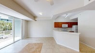 Located at 4341 Cortina Cir in Fort Myers, Florida, this three-story, three-bedroom, three-bathroom home offers a well-organized layout spread across three distinct levels. The ground floor houses an attached garage with automatic opener, a water heater, and utility access, providing practical storage and parking. The main living level features a bright, open-concept space that seamlessly connects the living room, dining area, and kitchen. Light tile flooring, a tray ceiling with a ceiling fan, and a sliding glass door leading to an outdoor balcony give this floor an airy, welcoming feel. The kitchen stands out with rich wood cabinetry, a classic subway tile backsplash, a sweeping marble-look countertop with a breakfast bar, and white appliances. The upper floor is home to the bedrooms, including a well-proportioned primary bedroom featuring vaulted ceilings, plush carpet, and a striking arched window that floods the room with natural light and outdoor views. The bathrooms are finished with wood-tone vanities, marble-look countertops, tile flooring, and glass-enclosed walk-in showers. A dedicated laundry room with a full-size washer and dryer adds everyday convenience. Multiple closets and a hallway complete the upper level, making this home both functional and comfortable.