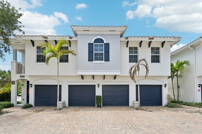 Charming Mediterranean architecture, featuring a tiled roof and vibrant palm trees, offering spacious two-car garages. - Bridgewater at Lake Osborne