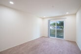 Located at 781 Fletcher Ln in Hayward, California, this one-bedroom, one-bathroom unit offers a functional and efficiently designed single-floor layout. The combined kitchen and living area serves as the heart of the home, where warm-toned wood cabinetry lines the kitchen walls above tile flooring, complemented by recessed lighting overhead. White appliances, including a range and refrigerator, are neatly integrated into the space. The living area transitions seamlessly from the kitchen, featuring plush carpeting and a sliding glass door that opens to an outdoor balcony, allowing natural light to fill the room and offering views of the surrounding neighborhood and greenery. A carpeted hallway connects the main living space to the private bedroom, which is a generously sized room with a large window framing tree-lined outdoor views, recessed lighting, and soft carpet flooring. The bathroom is clean and straightforward, appointed with a full-size soaking tub and shower combination with chrome fixtures and white tile surround. A dedicated closet provides additional storage. Throughout the unit, neutral cream-toned walls and consistent recessed lighting create a bright, cohesive ambiance well-suited for comfortable everyday living.