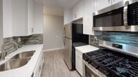 Located in the heart of West Hollywood at 1538 N Vista Street, this single-floor unit sits within a multi-story stucco building surrounded by lush tropical landscaping, including mature palm trees and banana plants, giving the property a distinctly Southern California character. The building's courtyard-facing balconies and tiled exterior pathways add to its welcoming ambiance.

Inside, the unit has been thoughtfully renovated throughout. The kitchen is a standout feature, outfitted with crisp white shaker cabinetry, sleek bar-pull hardware, and bright quartz countertops. A mosaic glass tile backsplash adds visual interest, while stainless steel appliances — including a gas range, over-the-range microwave, and refrigerator — complete the space. Light wood-tone flooring runs through the kitchen and into the adjoining areas, lending warmth and continuity.

The living area is generously proportioned, finished with the same wood-look flooring and neutral gray walls. Recessed lighting illuminates the open space evenly, creating a clean and versatile environment.

The bedroom is a calm, well-sized room with a window overlooking the courtyard's greenery, allowing natural light to filter in. The bathroom features white shaker vanity cabinetry with quartz countertops, a large mirror, wood-look tile flooring, and a full tub with floor-to-ceiling tile surround, offering a polished and functional finish throughout.