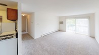 Located at 8507 S 88th Ter in Justice, IL, this single-floor residence offers a straightforward and functional layout designed for comfortable everyday living. The expansive main living area is finished with neutral wall-to-wall carpeting and features a large sliding glass door that floods the space with natural light while providing access to an outdoor area. A window-unit air conditioner and baseboard heating ensure year-round climate control throughout the home.

The kitchen is equipped with rich, dark wood cabinetry providing ample storage, white countertops, a gas range, and a full-size refrigerator. Wood-look flooring runs through the kitchen, adding a practical and durable surface to this workspace. A hallway with a bi-fold closet door connects the kitchen to the rest of the home.

The bedrooms are generously sized, each finished with soft carpeting and bright white walls. Windows dressed with horizontal blinds allow natural light into each room while maintaining privacy. Baseboard heating units are present in the bedrooms as well, ensuring consistent warmth.

The bathroom features a wood-tone vanity with a single sink, a medicine cabinet mirror, white subway tile surrounding the tub-shower combination, and wood-look vinyl flooring, creating a clean and classic finish. Overall, the home presents a clean, neutral palette throughout, offering a versatile and move-in-ready living environment.