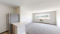 Located at 510 College Ave in Grand Rapids, Michigan, this studio unit offers a practical and well-designed open-concept layout that seamlessly combines the kitchen and living room into a single, efficient space. The living area is finished with soft wall-to-wall carpeting and neutral light gray walls, creating a clean and inviting atmosphere. A large picture window dominates the exterior wall, allowing natural light to fill the room while framing views of the surrounding Grand Rapids neighborhood. A wall-mounted PTAC unit and baseboard heating ensure year-round climate control.

The kitchen transitions naturally from the living space via a partial dividing wall with a white countertop peninsula, providing both a functional workspace and a visual boundary between the two areas. Light wood-tone cabinetry lines the kitchen walls, complemented by light hardwood-style flooring. Stainless steel appliances — including a refrigerator, electric range, built-in microwave, and dishwasher — give the kitchen a modern, cohesive look. The stainless steel sink adds a polished finishing touch. Overall, the space presents a bright, functional, and contemporary feel well-suited for single-occupancy living in the heart of Grand Rapids.