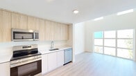 Located at 1715 N Dixie Hwy in Lake Worth Beach, Florida, this two-story residence offers a thoughtfully designed layout spread across two floors. The main level features an open-concept kitchen and living area filled with natural light from large windows. The kitchen is outfitted with stainless steel appliances — including a refrigerator, range, microwave, and dishwasher — complemented by light wood upper cabinetry, white lower cabinets, and clean white countertops. Light hardwood-style flooring runs throughout, enhancing the bright, airy feel of the space. The upper floor houses the spacious primary bedroom, which benefits from generous closet space — with a total of five closets throughout the home providing exceptional storage. Two full bathrooms serve the residence: one featuring a clean, minimalist vanity with modern fixtures, and the other offering a tiled soaking tub and shower combination with neutral stone-toned tile surround. An in-unit laundry area adds everyday convenience. The overall aesthetic is clean and contemporary, with a consistent palette of whites and natural wood tones that creates a cohesive, modern ambiance throughout this well-appointed Lake Worth Beach home.