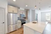 This well-appointed 2-bedroom, 2-bathroom residence in Framingham, MA offers a thoughtfully designed single-level floor plan with a clean, contemporary aesthetic throughout. The open-concept living area seamlessly connects the kitchen, dining, and living spaces, all finished with light hardwood-style flooring that enhances the bright, airy atmosphere. Large windows allow natural light to pour in, offering pleasant views of surrounding greenery.

The modern kitchen is a standout feature, showcasing light wood cabinetry, a subway tile backsplash, quartz countertops, and a spacious center island with a built-in sink and pendant lighting overhead. Stainless steel appliances, including a refrigerator, range, and microwave, complete this stylish and functional space.

Both bedrooms are comfortably sized, carpeted for warmth, and include windows with natural views. The generously sized primary bedroom benefits from ample closet space. In total, the residence includes four closets, providing excellent storage throughout. The bathrooms are finished with modern tile flooring, clean-lined vanities with light wood cabinetry, and a glass-enclosed walk-in shower. Additional conveniences include a dedicated laundry area and utility room, rounding out this move-in-ready home.
