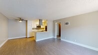 Located at 7400 Parkway Dr in La Mesa, California, this single-floor unit offers a practical and well-appointed layout with a clean, neutral aesthetic throughout. The open-concept living and kitchen area serves as the heart of the space, where wood-look plank flooring extends across the room and a textured ceiling adds character overhead. A ceiling fan provides additional comfort in the living area, which flows seamlessly toward the entry door and features a wall-mounted HVAC unit for climate control.

The kitchen is thoughtfully designed with white shaker-style cabinetry, a subway tile backsplash, light countertops, and stainless steel appliances including a built-in microwave and dishwasher. A stainless steel range hood anchors the peninsula, which provides both additional prep space and a casual dining option, separating the kitchen from the open living zone.

The bedroom is carpeted for comfort and features a window with views of surrounding greenery, allowing natural light to fill the room. An adjacent hallway leads to the bathroom, which is outfitted with a white vanity, undermount sink, brushed nickel hardware, a large mirror, and a clean tub-shower combination. The space also includes an electrical panel accessible from the hallway, adding functional convenience.