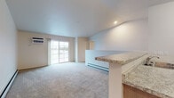Located at 1300 Pleasant Dr in Plover, Wisconsin, this two-floor unit offers a practical and well-appointed layout designed for comfortable everyday living. The kitchen serves as a functional centerpiece, featuring a galley-style configuration with taupe cabinetry, light granite-style countertops, stainless steel appliances including an electric range, microwave, and refrigerator, and durable wood-look vinyl flooring. A peninsula counter connects the kitchen to the open living area, which is finished with plush carpeting and includes a sliding glass door that allows natural light and provides access to outdoor views. Baseboard heating runs throughout, ensuring efficient warmth during Wisconsin winters, and wall-mounted air conditioning units offer cooling comfort.

The bedrooms are carpeted and equipped with ceiling fans and windows that bring in natural light. The bathroom features a walk-in shower with a built-in seat, granite-topped vanity, and taupe cabinetry consistent with the rest of the unit's finishes. A dedicated laundry room with wire shelving accommodates a full-size washer and dryer. Carpeted stairs lead between floors, and the attached garage provides convenient enclosed parking with interior access.